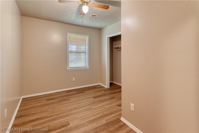 unfurnished bedroom featuring ceiling fan, a closet, a textured ceiling, and light wood-type flooring