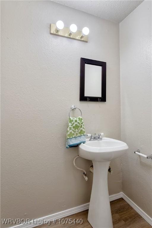 bathroom with hardwood / wood-style floors and a textured ceiling