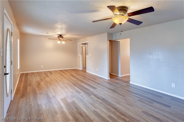 empty room featuring a textured ceiling, light wood-type flooring, and ceiling fan