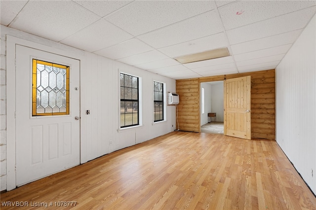 foyer featuring rustic walls, a wall mounted air conditioner, a drop ceiling, and light hardwood / wood-style flooring