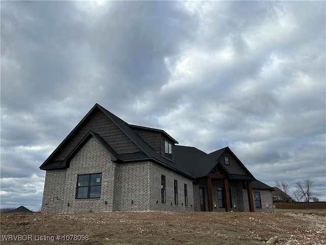 view of side of home with fence and brick siding