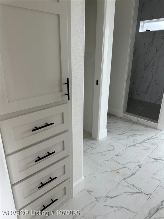 bathroom featuring baseboards, marble finish floor, and a marble finish shower