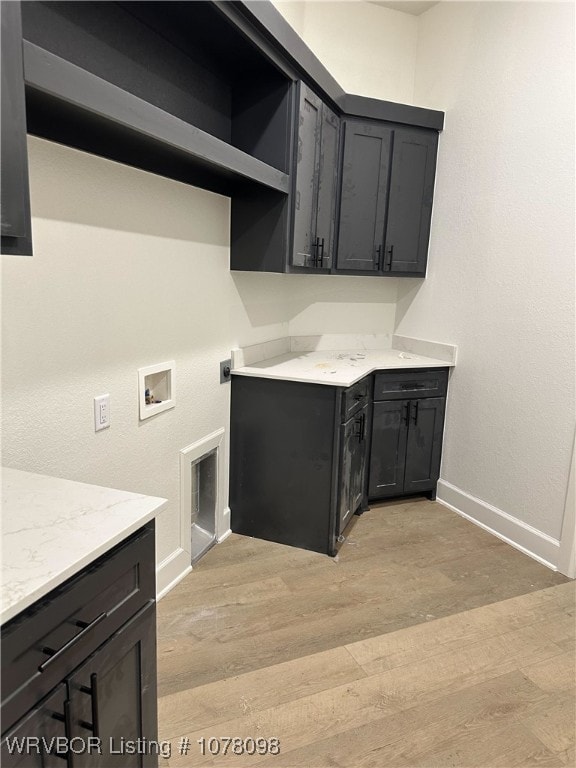 laundry area featuring baseboards, cabinet space, hookup for a washing machine, and light wood-type flooring