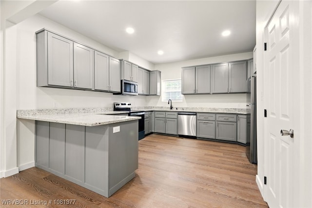925 Cedar St, Van Buren, AR 72956 - kitchen featuring stainless steel appliances, gray cabinets, a peninsula, light stone countertops, and light wood-style floors