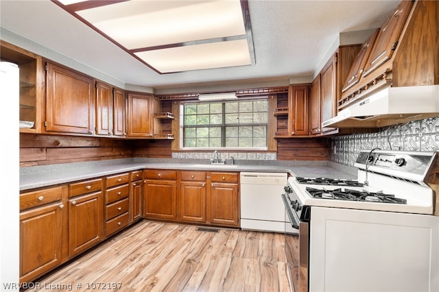 kitchen with light wood-type flooring, backsplash, white appliances, sink, and range hood