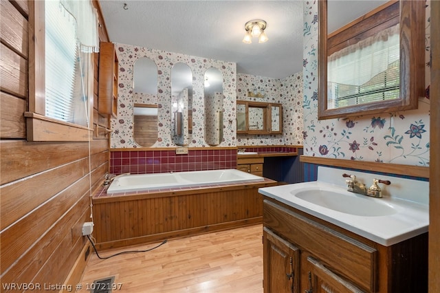 bathroom with vanity, a tub to relax in, wood-type flooring, and a textured ceiling