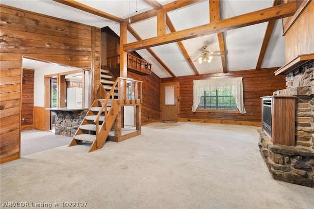 living room featuring ceiling fan, lofted ceiling with beams, wood walls, light colored carpet, and a fireplace