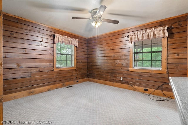 empty room featuring carpet, ceiling fan, and wooden walls