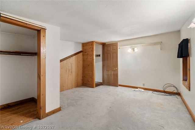 unfurnished bedroom featuring light colored carpet, a closet, and wooden walls