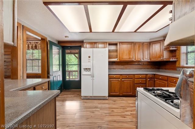 kitchen with light wood-type flooring, white appliances, and custom exhaust hood