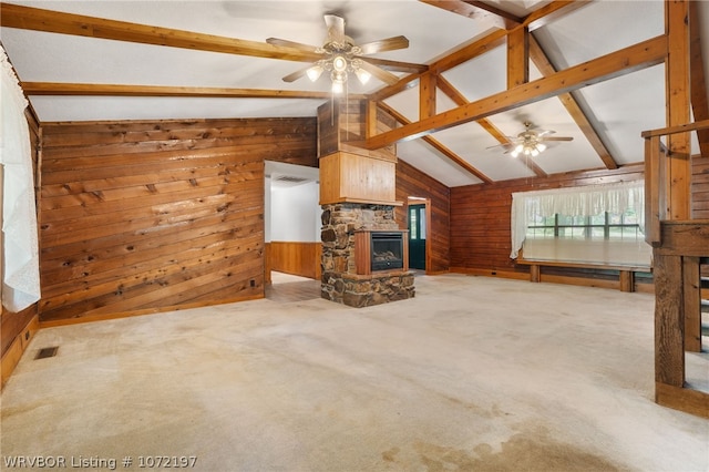 unfurnished living room featuring carpet flooring, ceiling fan, wooden walls, a fireplace, and vaulted ceiling with beams