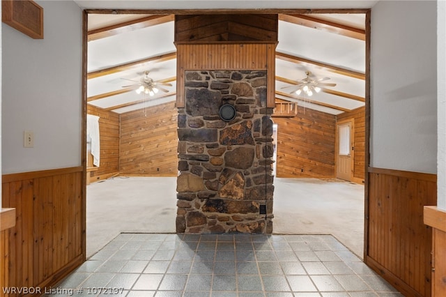 living room featuring carpet flooring, a stone fireplace, wooden walls, and lofted ceiling with beams