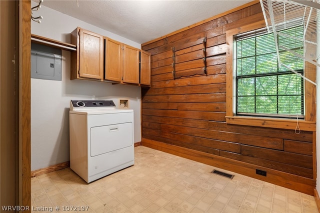 laundry room featuring cabinets, washer / clothes dryer, electric panel, a textured ceiling, and wooden walls