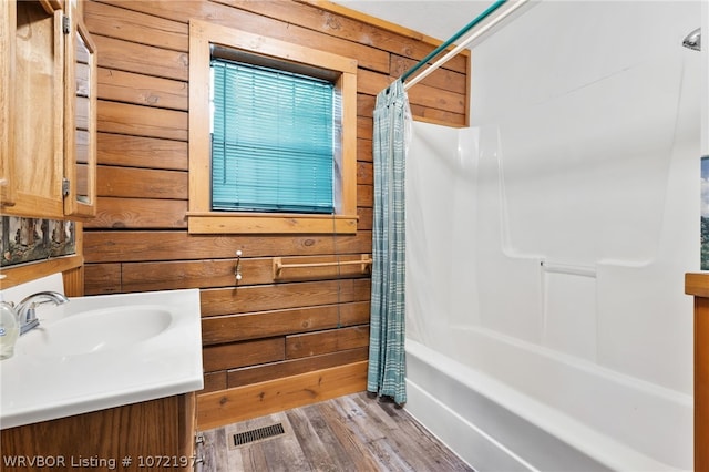 bathroom featuring hardwood / wood-style floors, shower / bath combo, vanity, and wooden walls