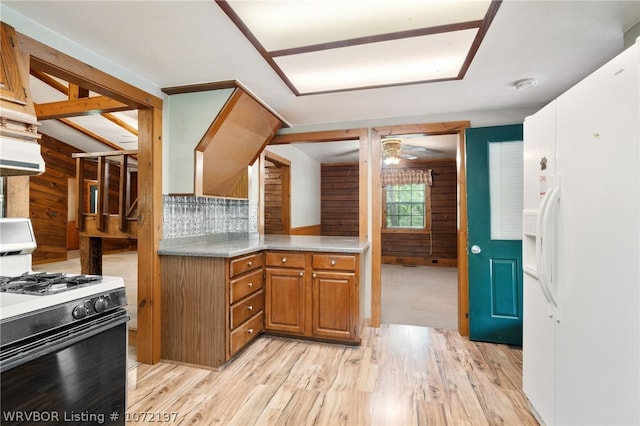 kitchen with white appliances, backsplash, wooden walls, ceiling fan, and light wood-type flooring