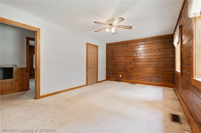 carpeted empty room with ceiling fan and wooden walls