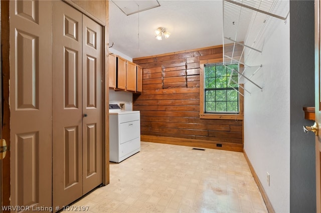 clothes washing area featuring cabinets, washer / dryer, and wooden walls