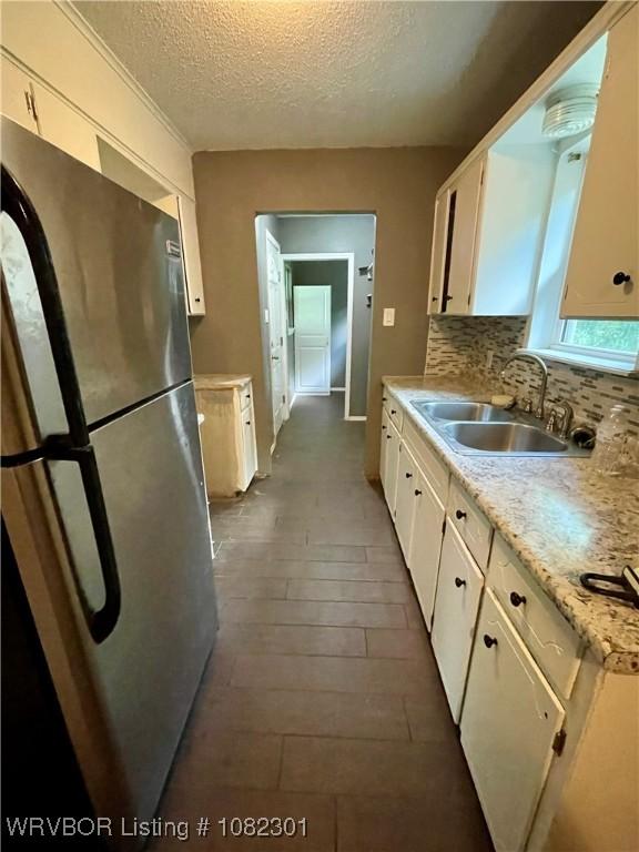 9423 Gate Nine Cutoff, Fort Smith, AR 72916 - kitchen with freestanding refrigerator, a textured ceiling, light countertops, white cabinetry, and decorative backsplash