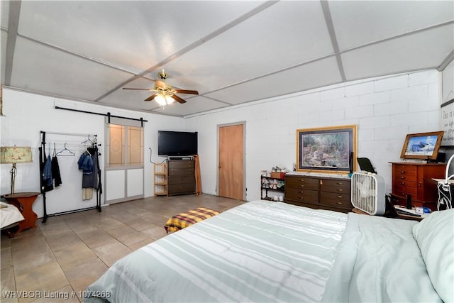 tiled bedroom with a barn door and ceiling fan