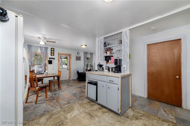 kitchen with gray cabinetry, ceiling fan, and white fridge