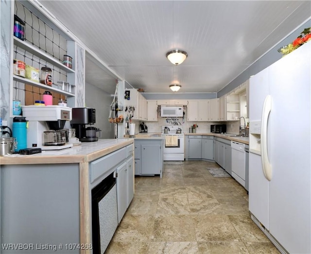 kitchen featuring decorative backsplash, white cabinetry, sink, and white appliances