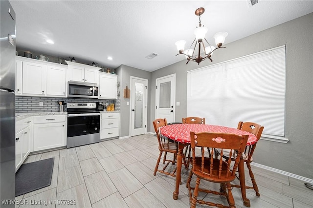 kitchen with a chandelier, pendant lighting, white cabinets, and stainless steel appliances