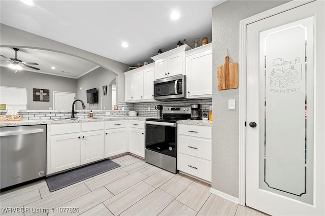 kitchen featuring white cabinetry, sink, ceiling fan, decorative backsplash, and appliances with stainless steel finishes