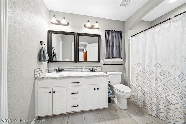 bathroom with vanity, toilet, and tasteful backsplash