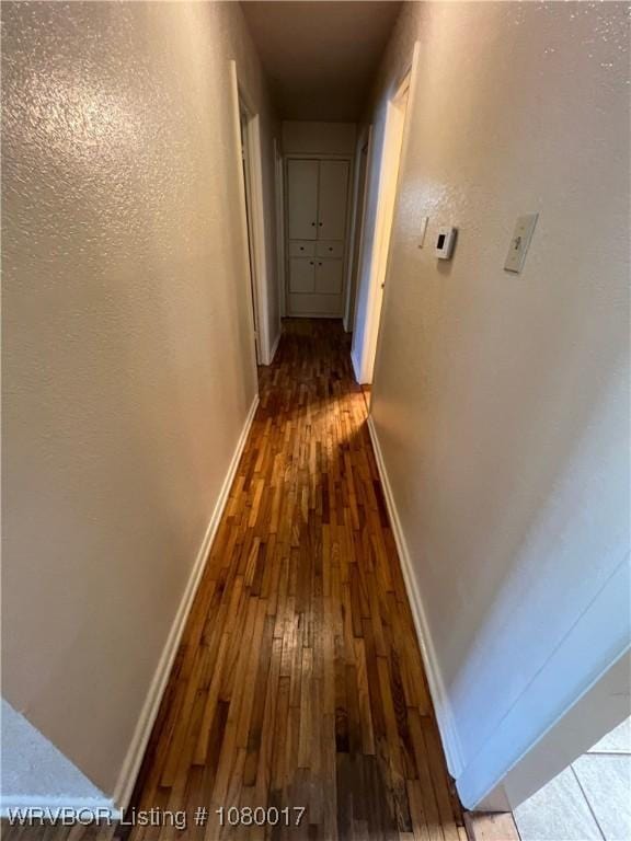 hall with baseboards and wood-type flooring