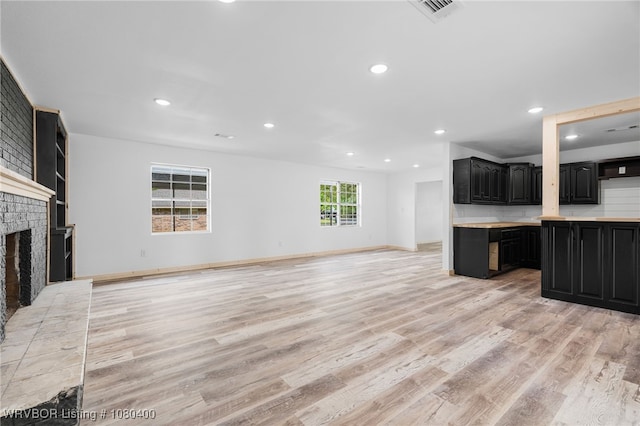 1703 E Edmondson Dr, Sallisaw, OK 74955 - unfurnished living room with light wood finished floors, recessed lighting, a brick fireplace, and baseboards