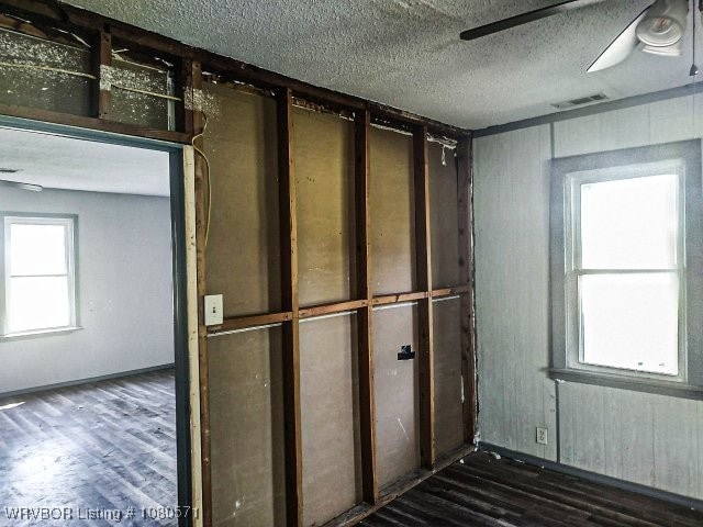 interior space with a textured ceiling, visible vents, ceiling fan, and dark wood finished floors