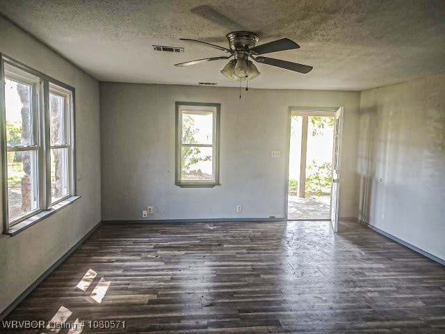 spare room featuring a textured ceiling, visible vents, ceiling fan, and dark wood-style floors
