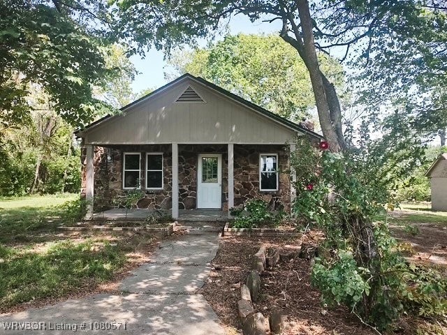 bungalow featuring a porch and stone siding