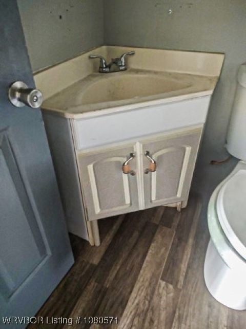 bathroom with toilet, wood finished floors, and vanity