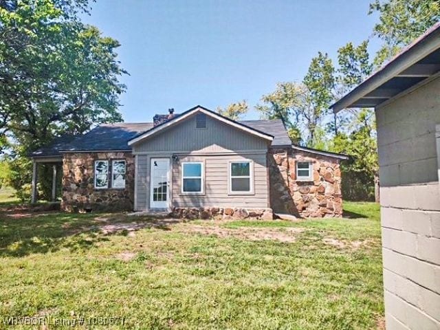 rear view of property featuring a lawn and stone siding
