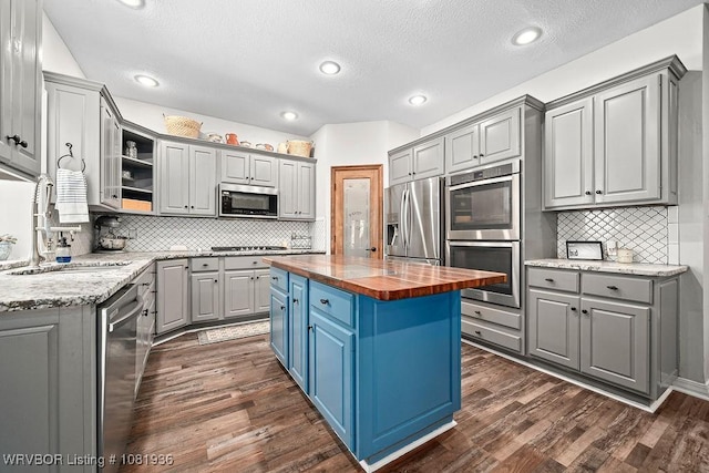 9301 Canopy Oaks Dr, Fort Smith, AR 72903 - kitchen with butcher block counters, stainless steel appliances, gray cabinets, decorative backsplash, and a kitchen island