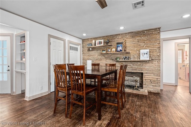 dining room featuring built in shelves, a fireplace, and dark hardwood / wood-style flooring