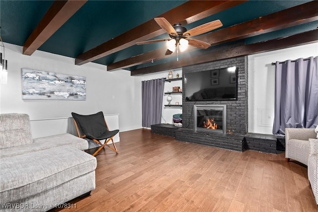 living room featuring ceiling fan, beam ceiling, wood-type flooring, and a fireplace