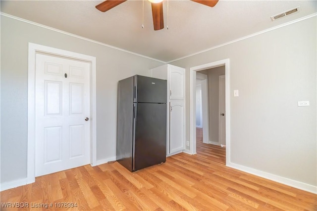 unfurnished bedroom with black fridge, ornamental molding, ceiling fan, and light hardwood / wood-style flooring