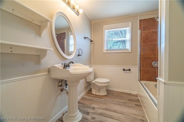 bathroom with toilet, hardwood / wood-style flooring, and combined bath / shower with glass door