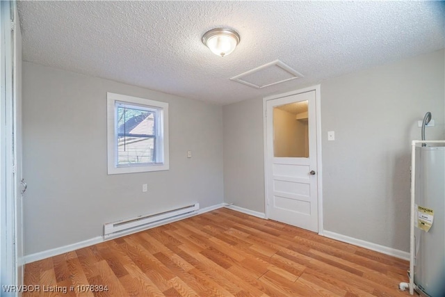 unfurnished room featuring light hardwood / wood-style floors, baseboard heating, secured water heater, and a textured ceiling