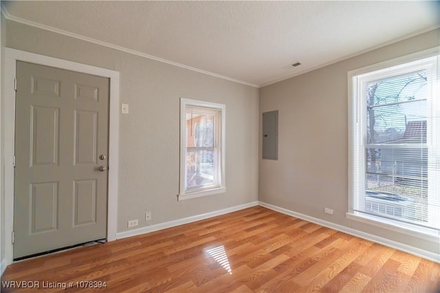 foyer entrance with ornamental molding, electric panel, and light hardwood / wood-style flooring