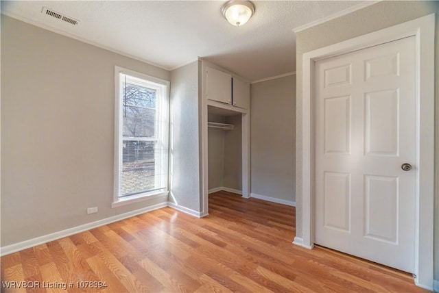 unfurnished bedroom featuring a closet, crown molding, and light hardwood / wood-style flooring