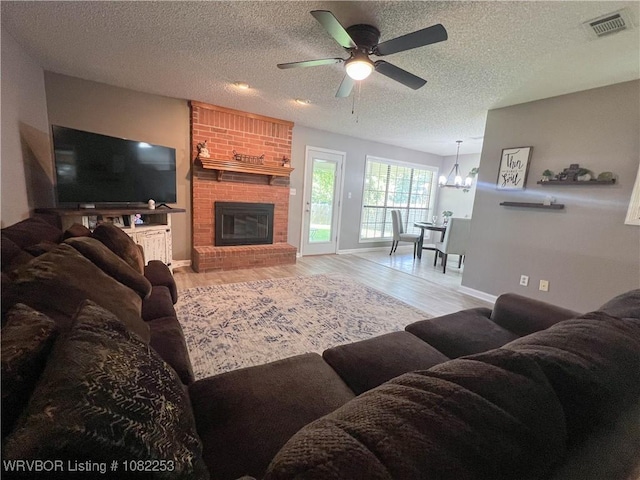 801 Northview Dr, Van Buren, AR 72956 - living area with a ceiling fan, wood finished floors, a fireplace, a textured ceiling, and a chandelier