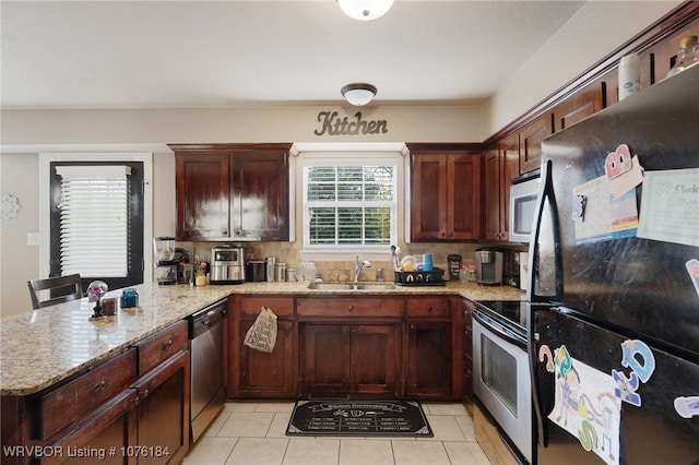 kitchen with kitchen peninsula, light stone countertops, sink, and stainless steel appliances