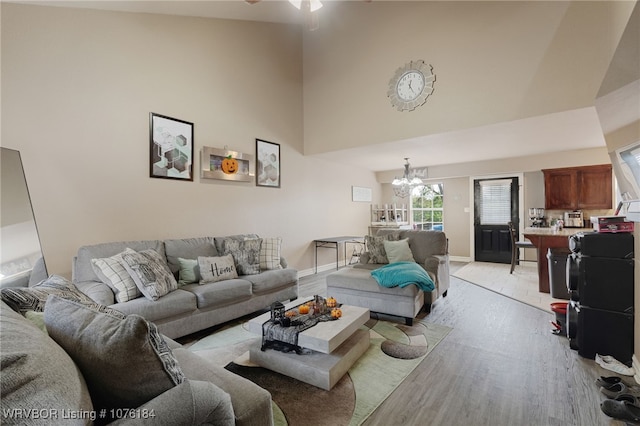 living room with a towering ceiling, light hardwood / wood-style floors, and ceiling fan with notable chandelier