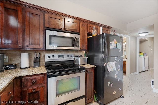 kitchen with light stone countertops, backsplash, stainless steel appliances, light tile patterned floors, and independent washer and dryer