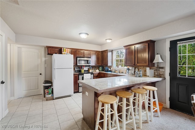 kitchen with kitchen peninsula, decorative backsplash, stainless steel appliances, and a healthy amount of sunlight