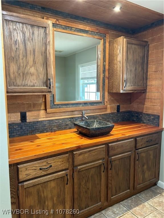 kitchen with butcher block countertops, wooden ceiling, tasteful backsplash, light tile patterned flooring, and sink