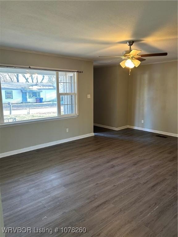 empty room featuring dark wood-type flooring, ornamental molding, and ceiling fan